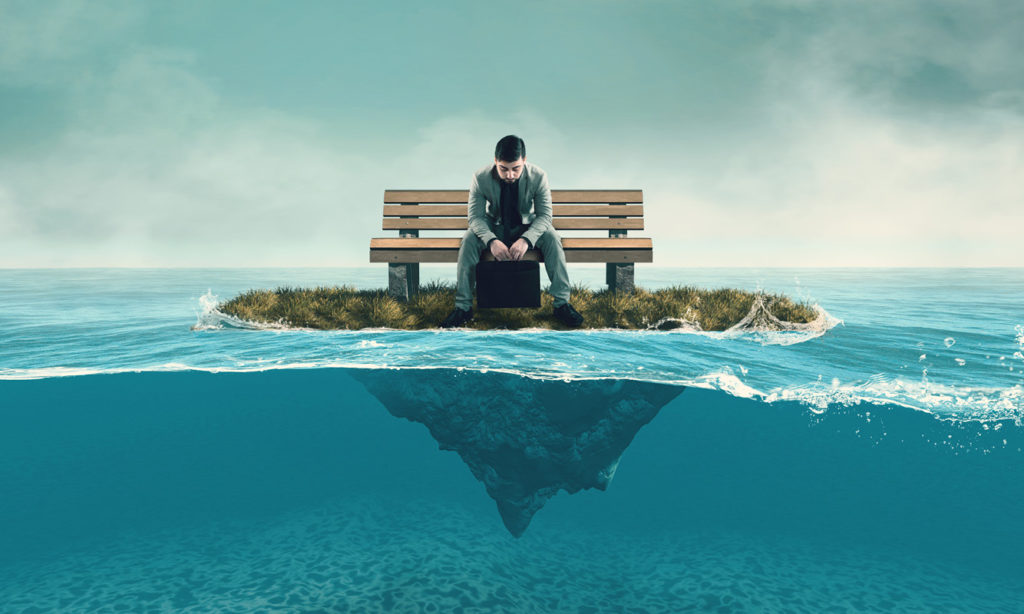 A man sitting on a tiny island surrounded by the sea